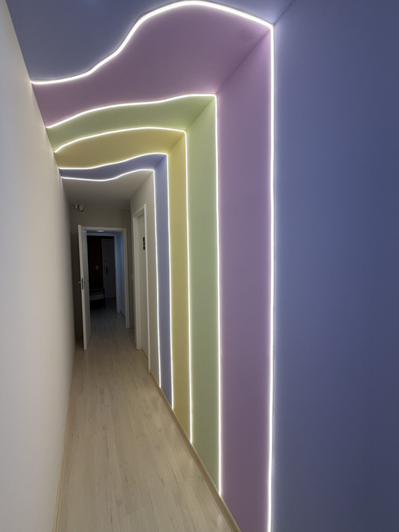 Corredor da Casa Telos com faixas de cor em curva contornadas por luz