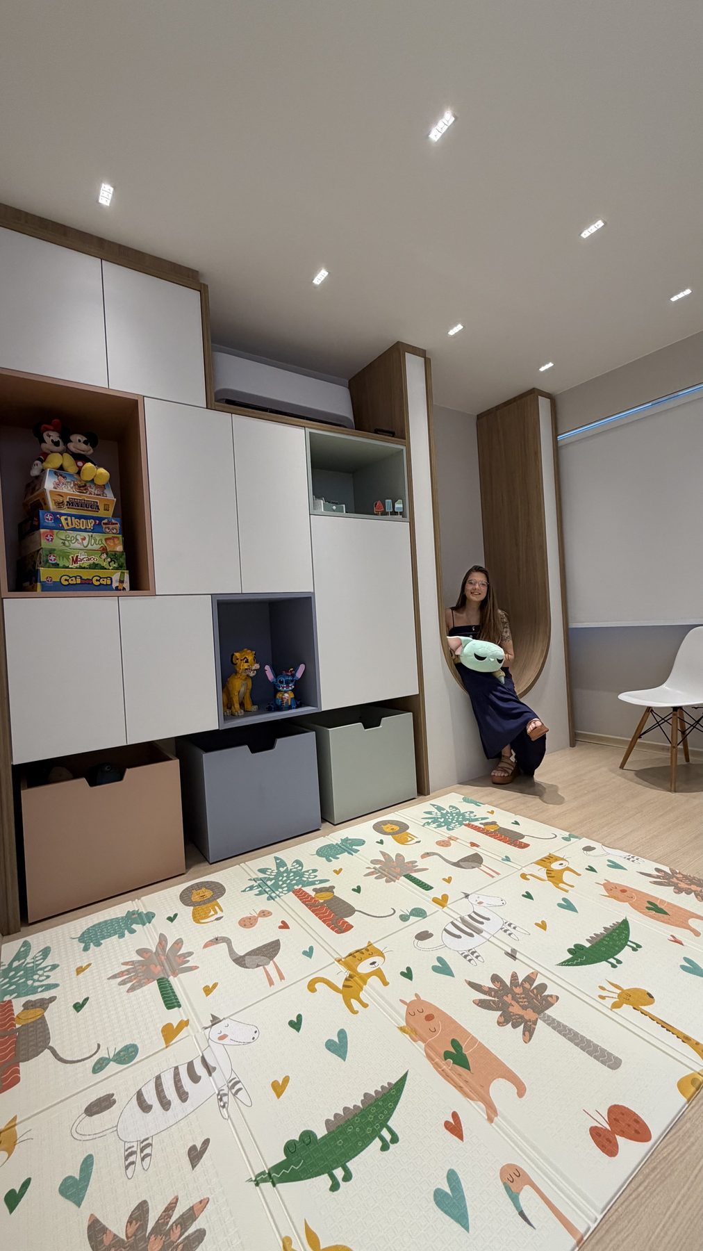 Marcenaria da sala infantil com nicho em arco, jogos, caixas de arrumação e tapete de brincar