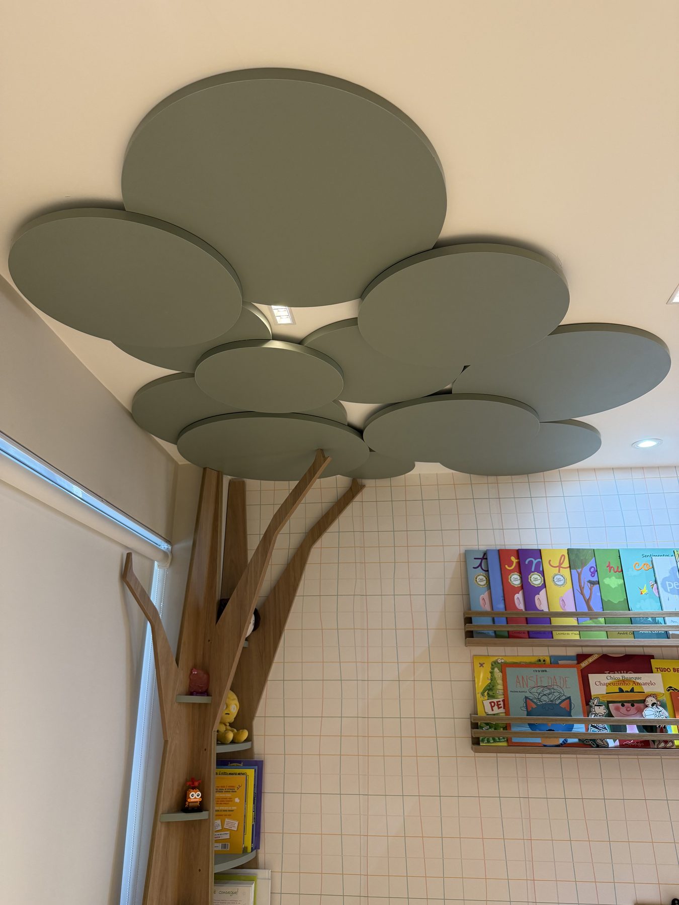 Estante em formato de árvore na sala infantil, com copa no teto e nichos no tronco
