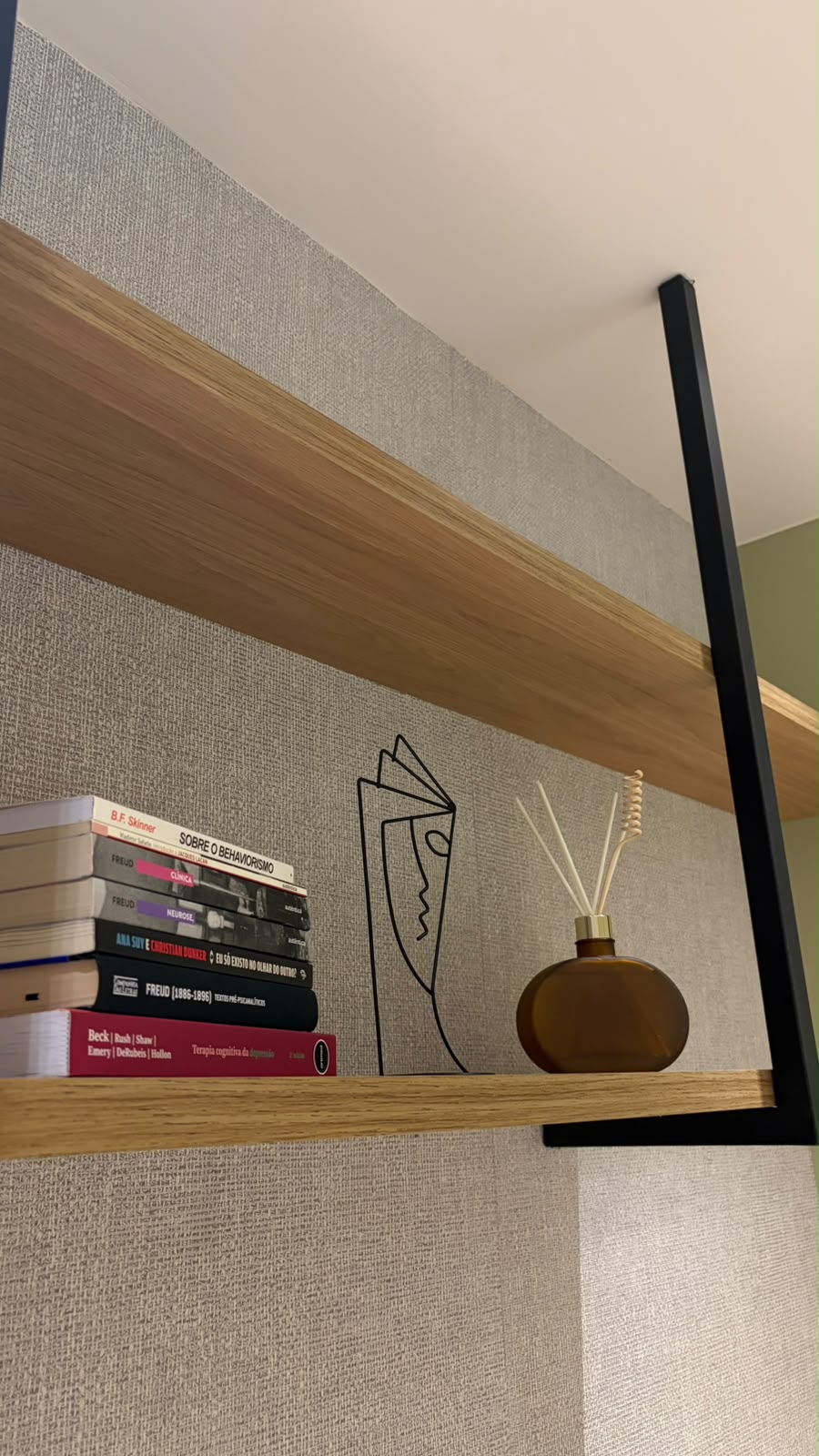 Prateleira de madeira com livros de psicologia e difusor de aromas
