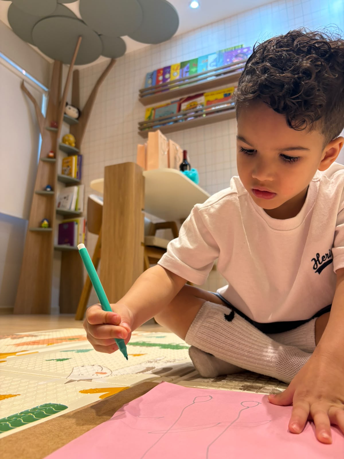 Criança desenhando no tapete da sala infantil